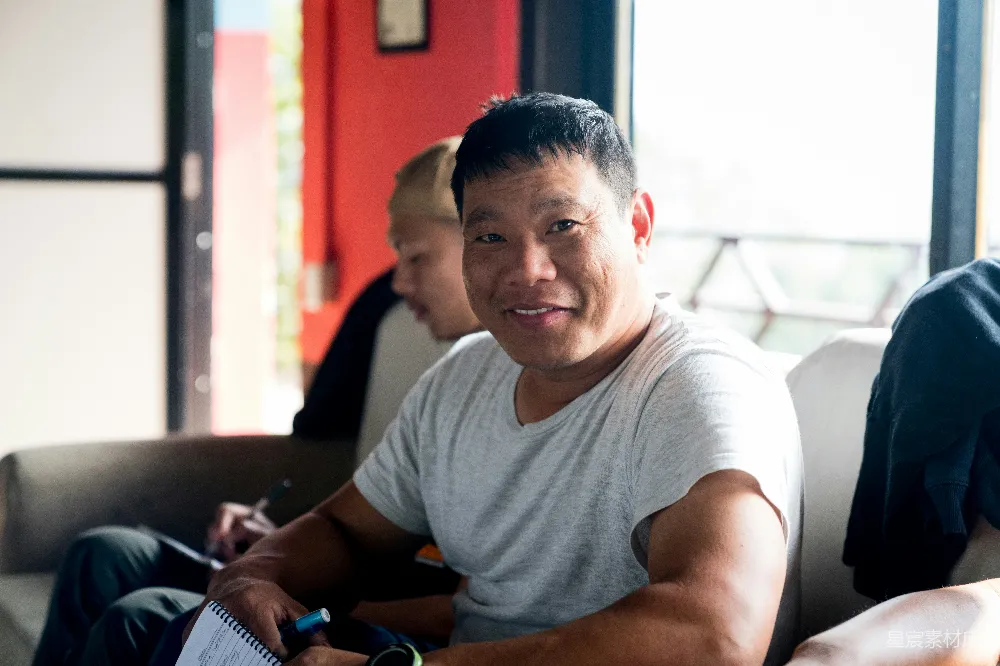 高清摄影  一个男人坐在沙发上，旁边还坐着另一个男人。