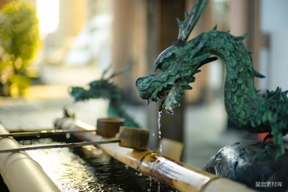 高清摄影  一张水泉的特写，背景中有一座龙雕像。