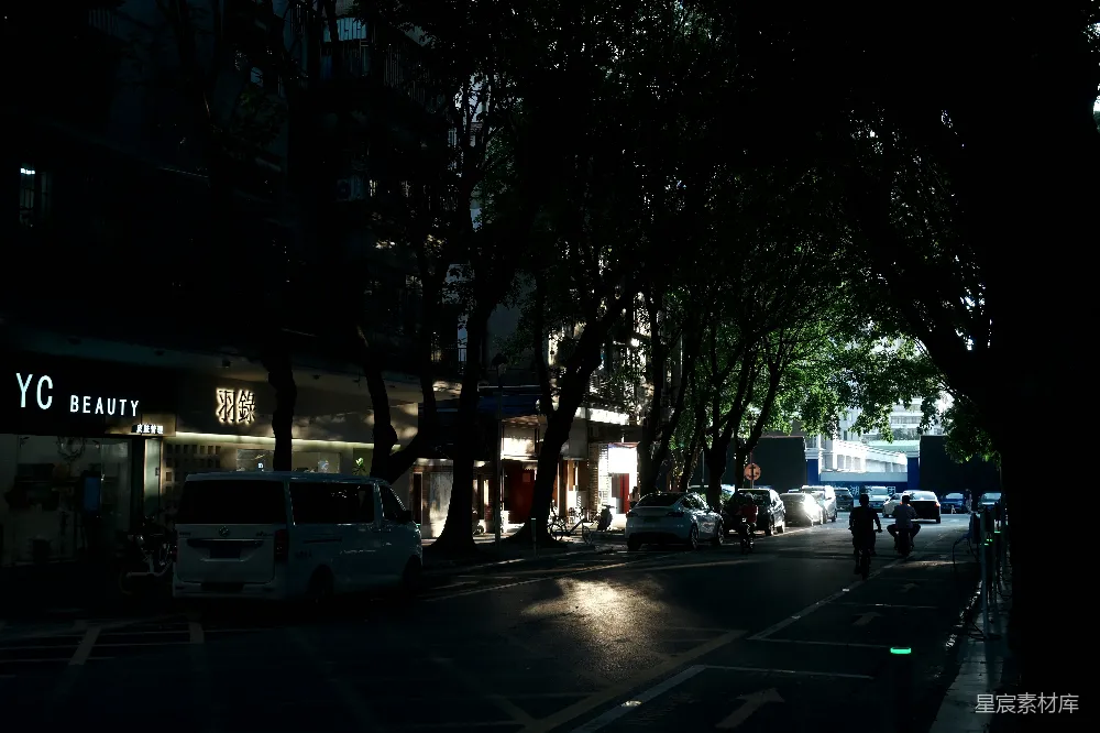 高清摄影  黑暗的城市街道，有汽车和树木。