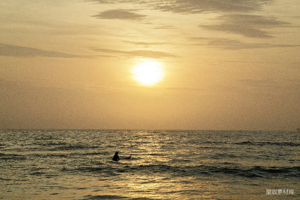 高清摄影  夕阳西下，一个人在海中冲浪。