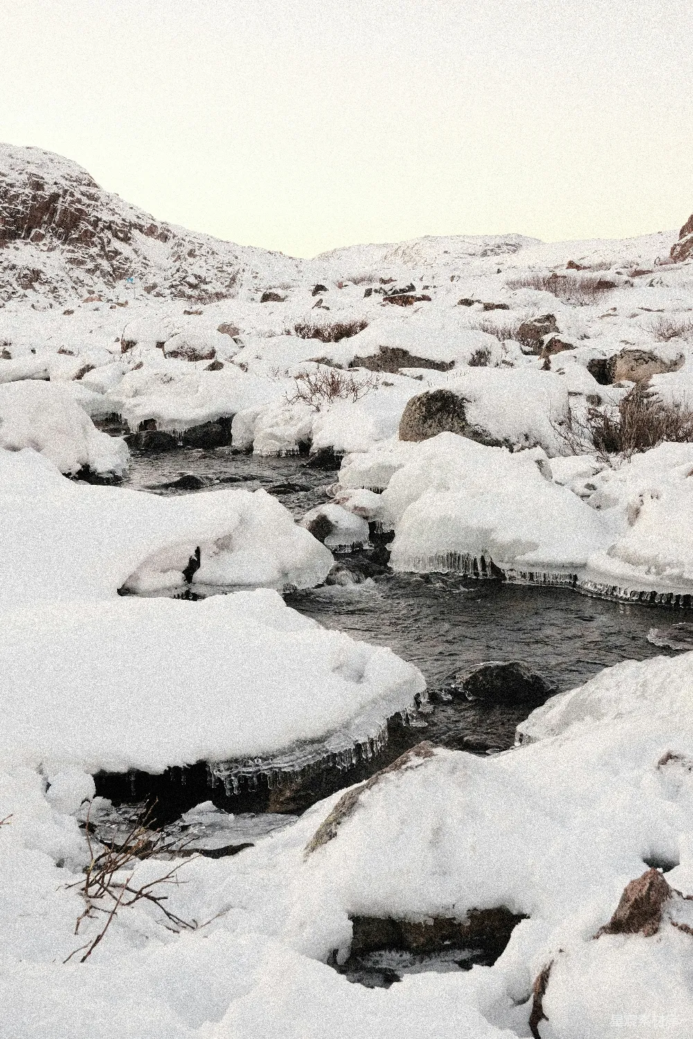 高清摄影  一条溪流环绕着积雪覆盖的岩石。