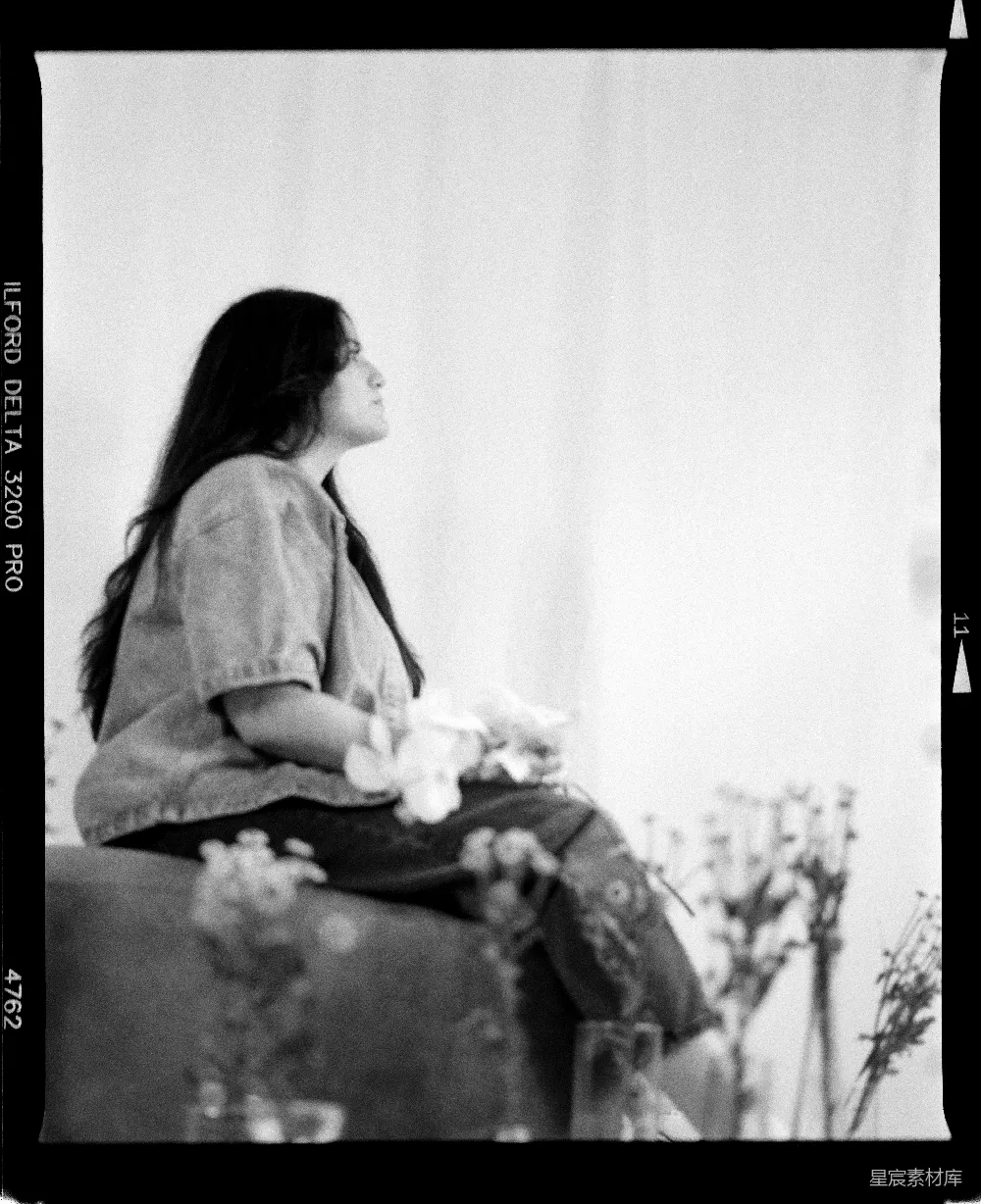 高清摄影  年轻女子坐在工作室里，手里拿着花。