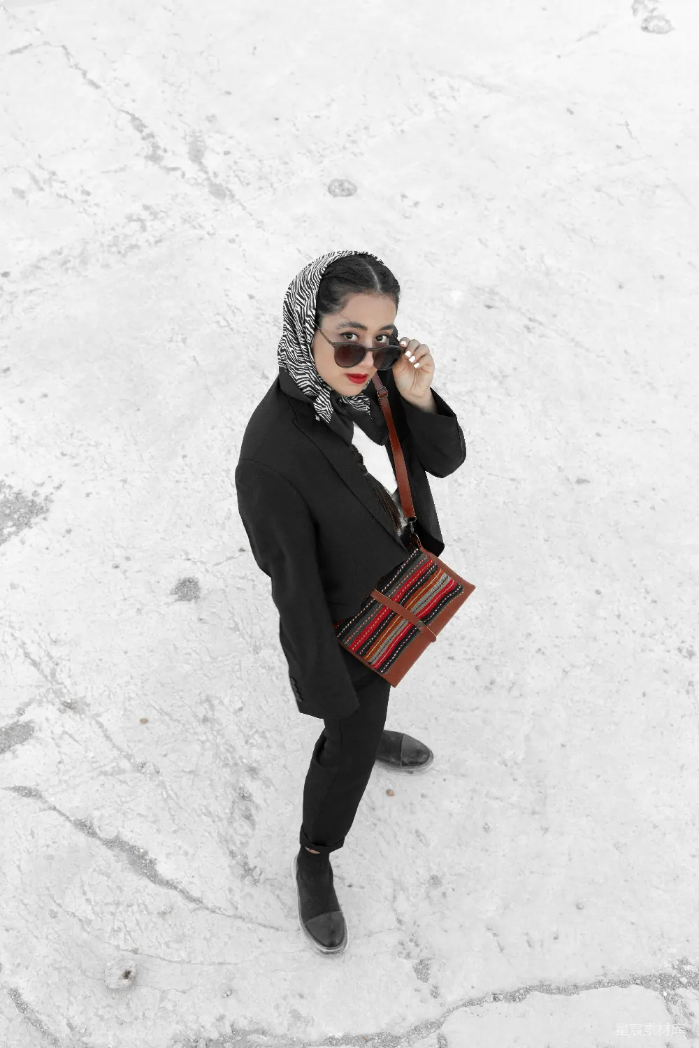高清摄影  一个戴着围巾、拎着钱包的女人站在雪地里。