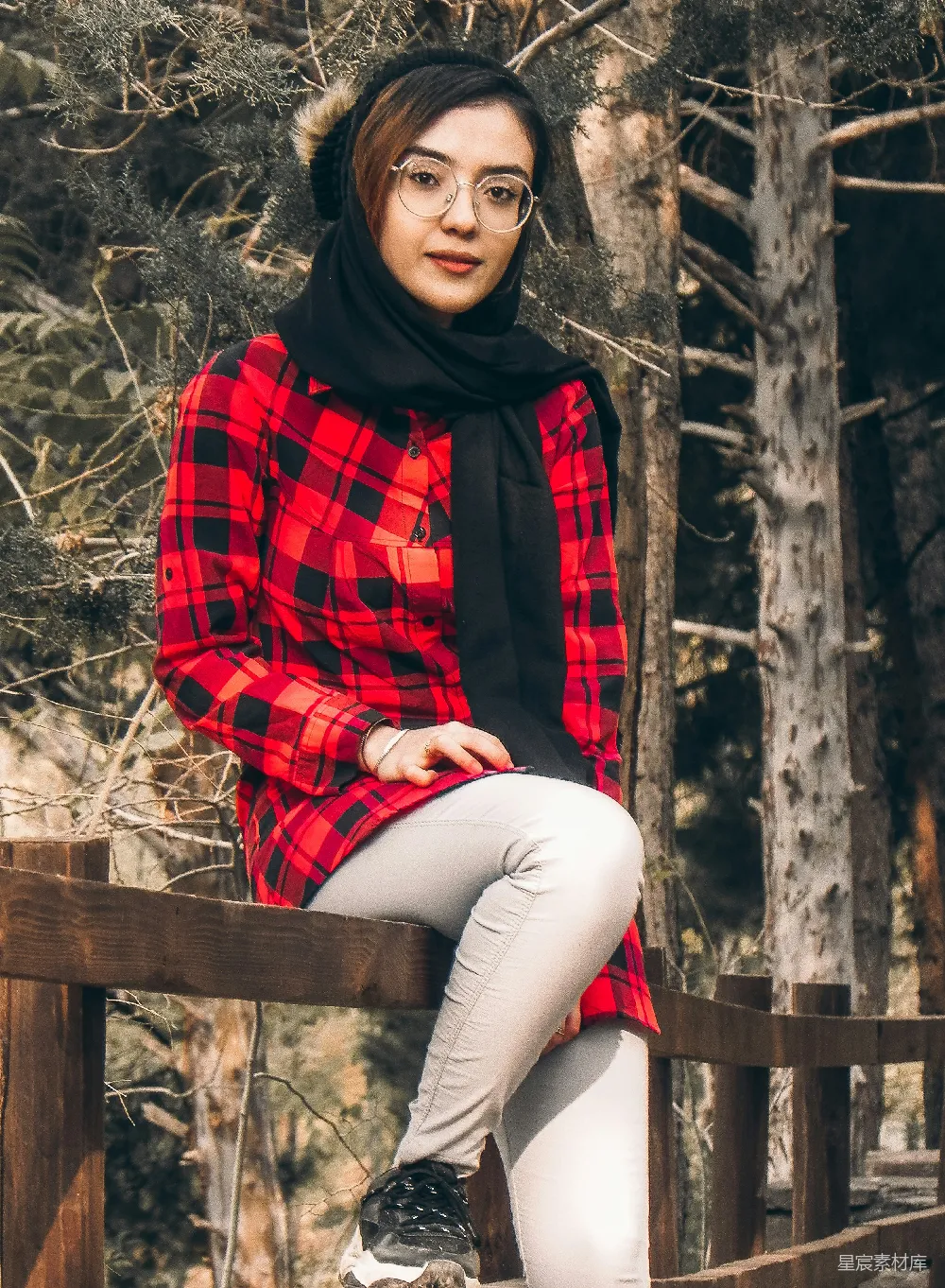 高清摄影  穿着红黑格子衬衫和白色裤子的女人坐在棕色木制长凳上。