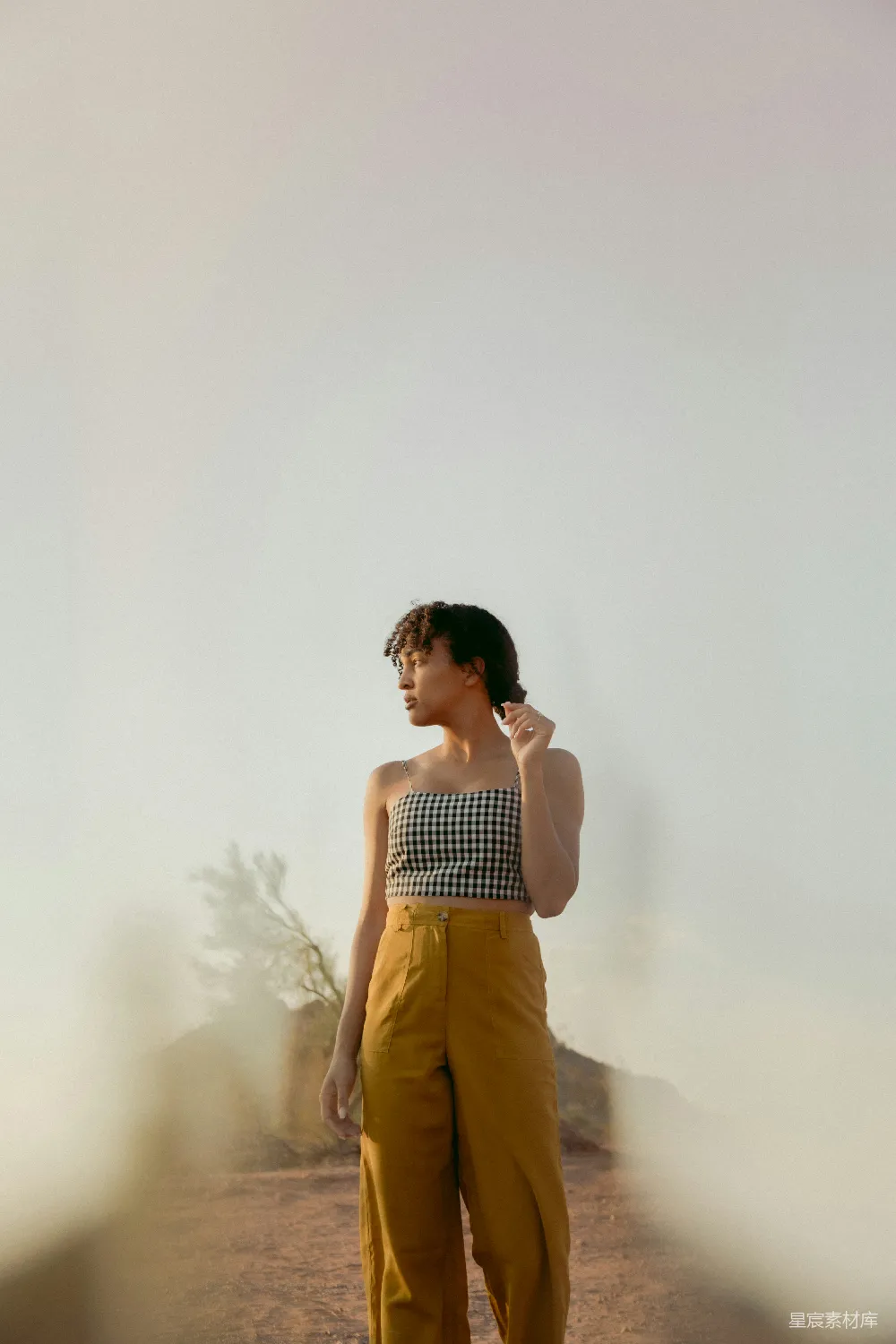 高清摄影 人物 穿着黑白条纹背心和棕色裤子的女人站在白色墙边。