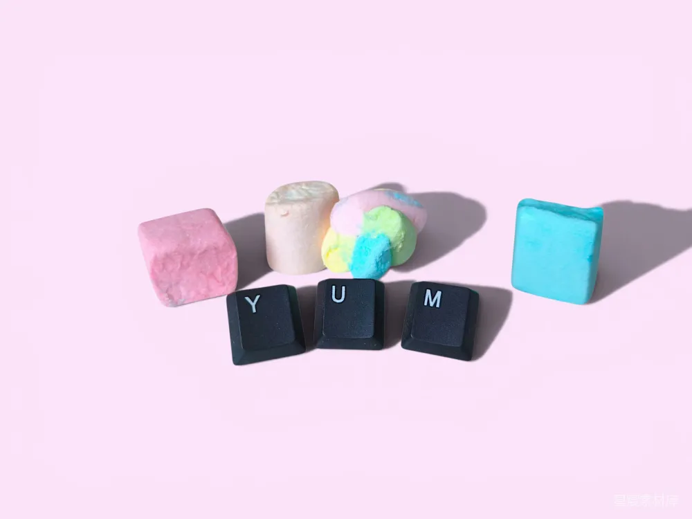 高清摄影  彩色棉花糖和“yum”键盘键在粉红色背景上。