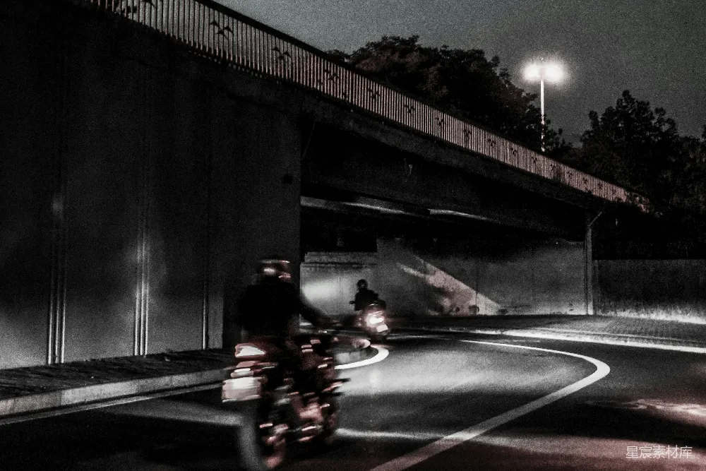 高清摄影  一个男人在夜晚沿着街道骑摩托车。