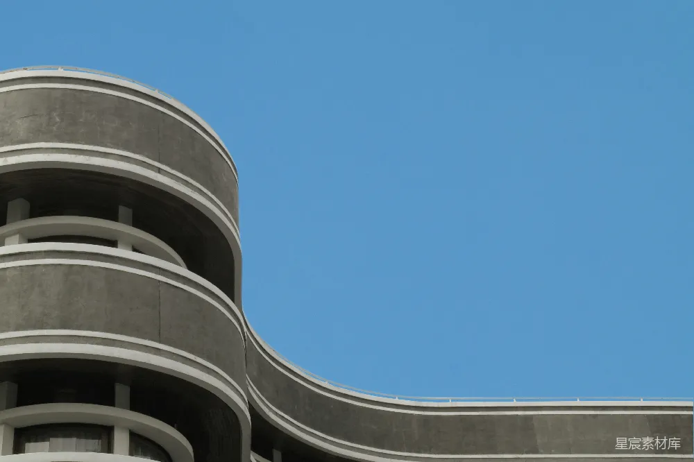 高清摄影  弯曲的混凝土建筑映衬在晴朗的蓝天之下。