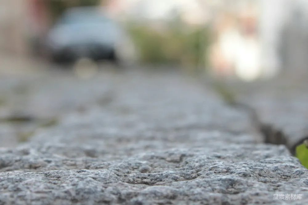 高清摄影  灰色纹理的石头表面通向模糊的街道。