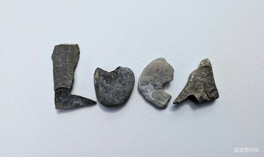 高清摄影  灰色的石头在白色背景上拼出“loca”。