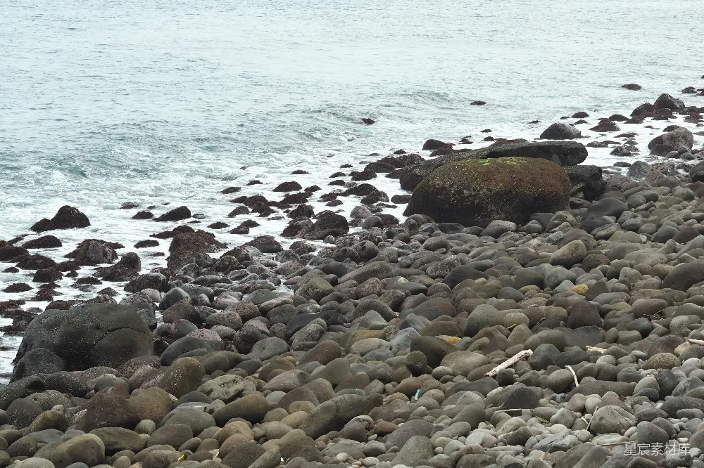 高清摄影  一个岩石海滩，海浪轻轻拍打着海岸。