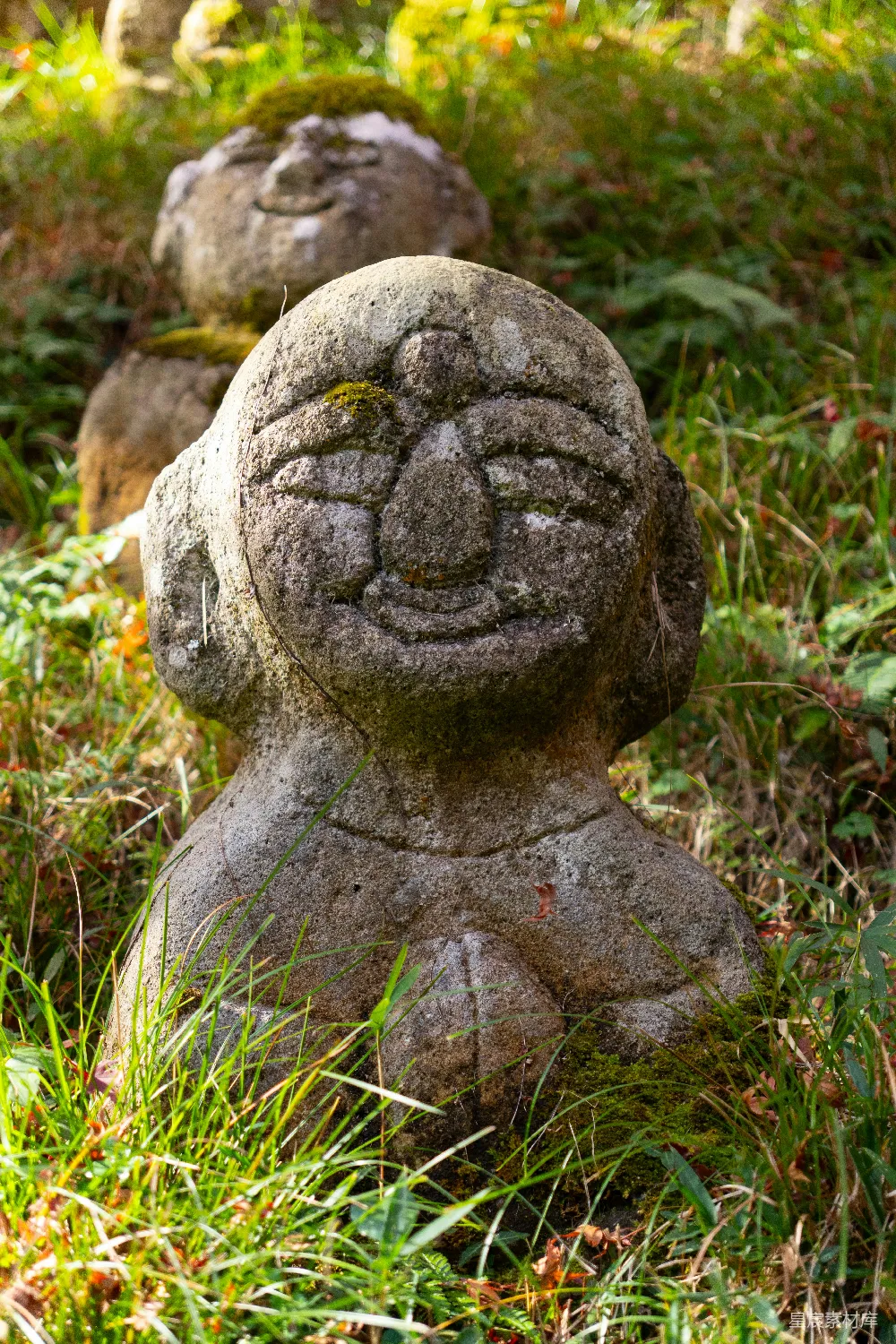 高清摄影  草地上的石雕，雕面上带着微笑。