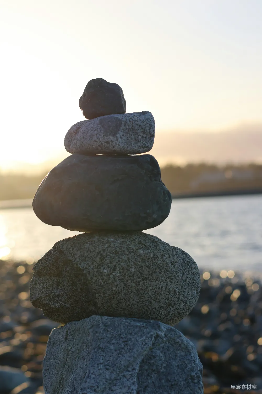 高清摄影  在夕阳下，海洋边的平衡石堆。