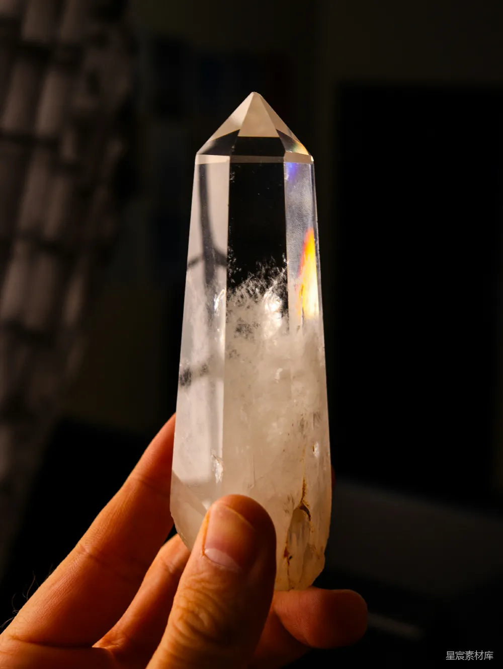 高清摄影  一只手拿着一块含有包裹体的透明水晶。