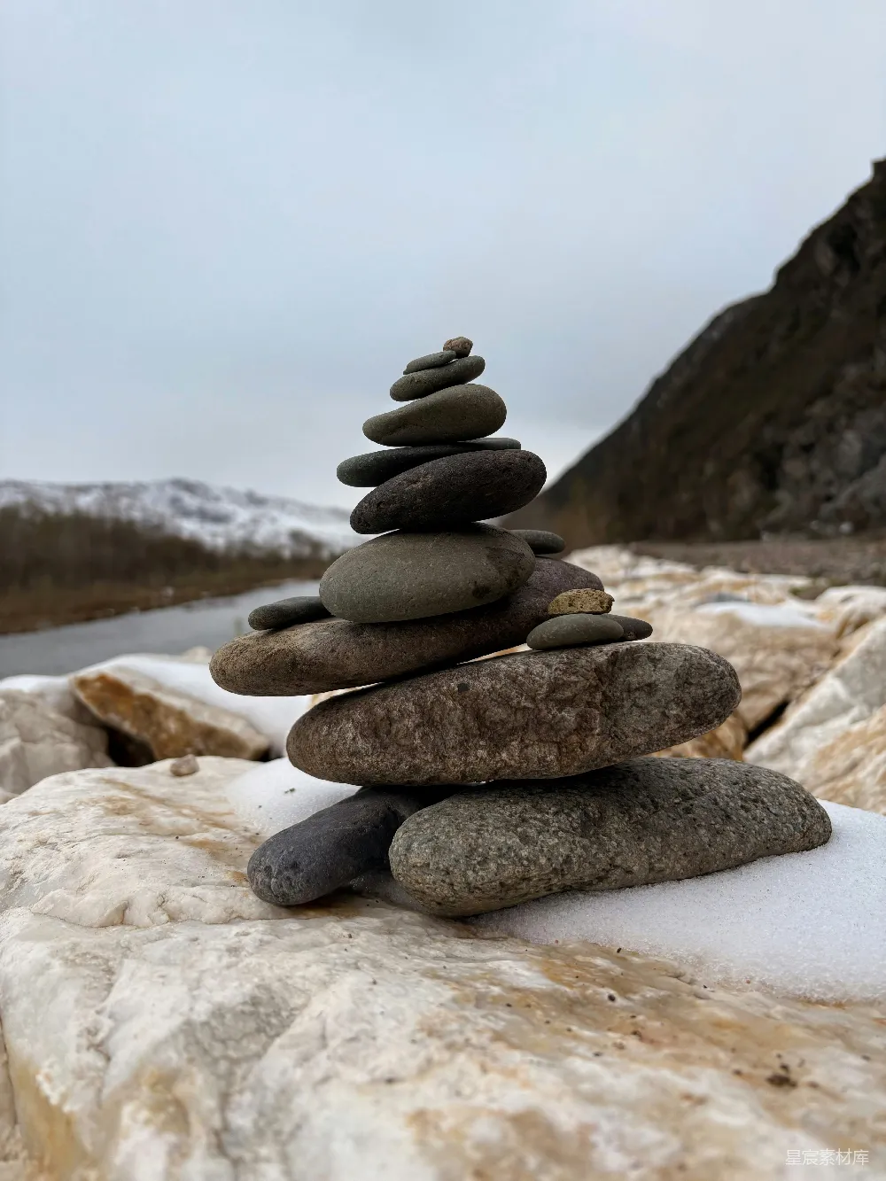 高清摄影  堆叠整齐的石头在雪岸上。