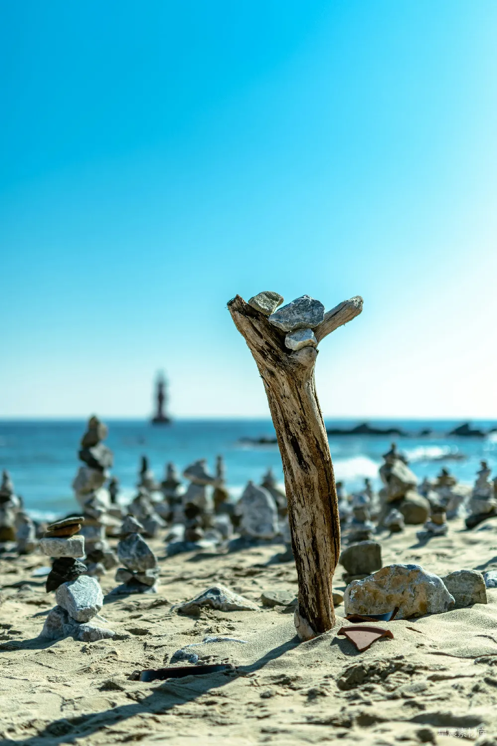高清摄影  阳光明媚的海滩上有漂流木和平衡的石头。