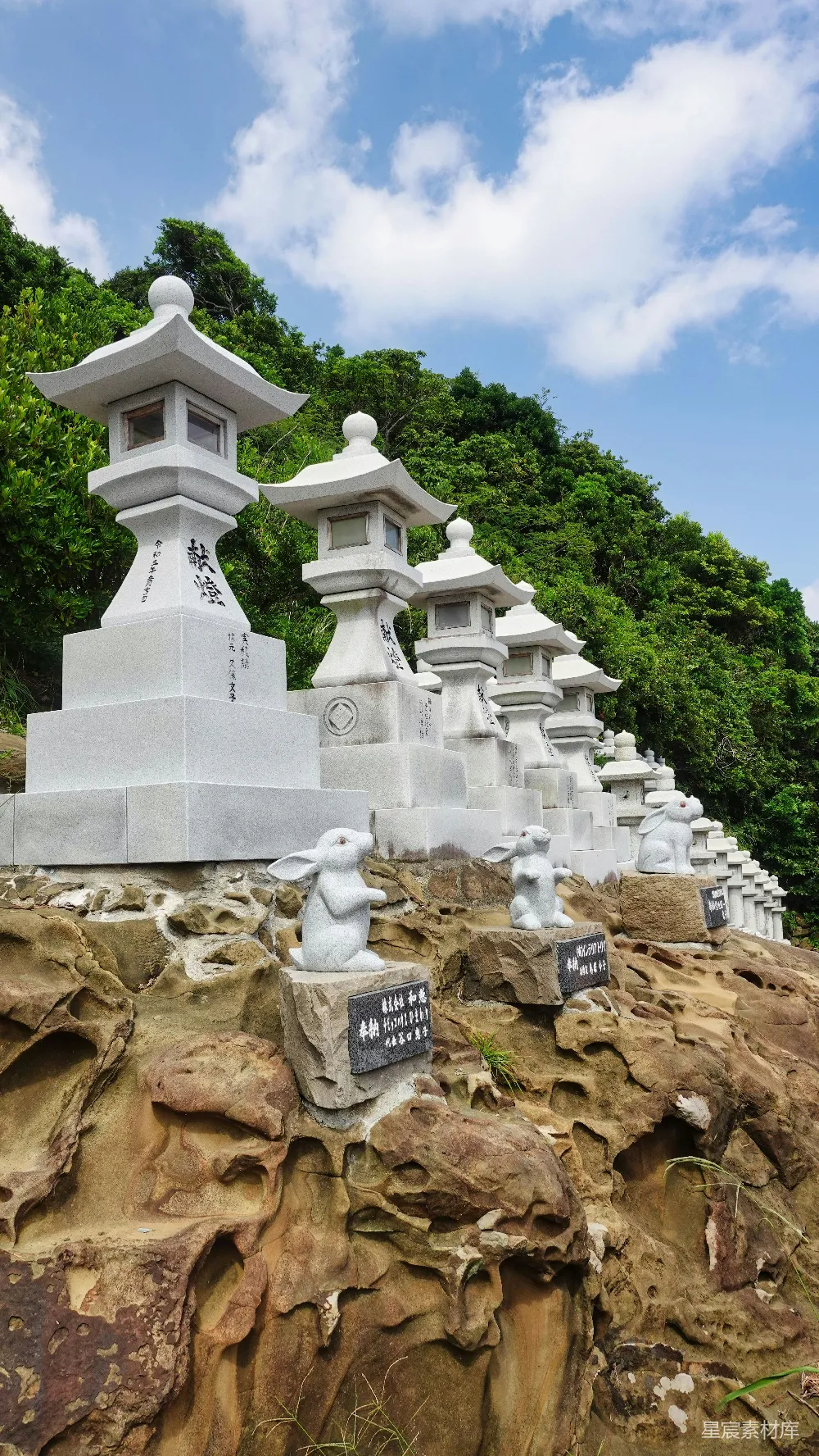 高清摄影  一群白色的雕像坐在岩石山坡上。