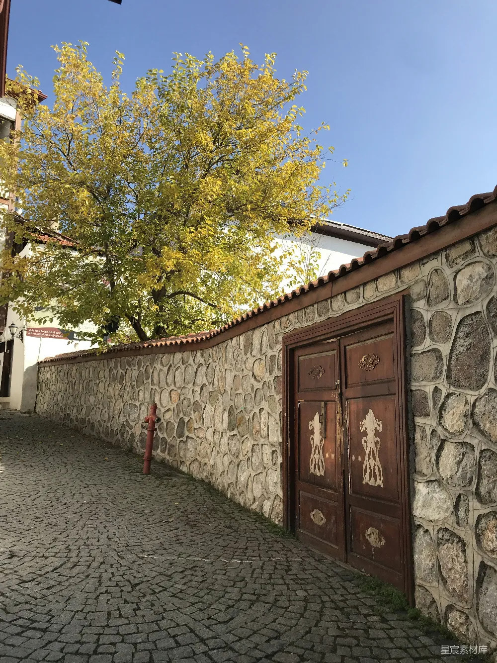 高清摄影  一条石板小径，背景中有一棵树和一座建筑。