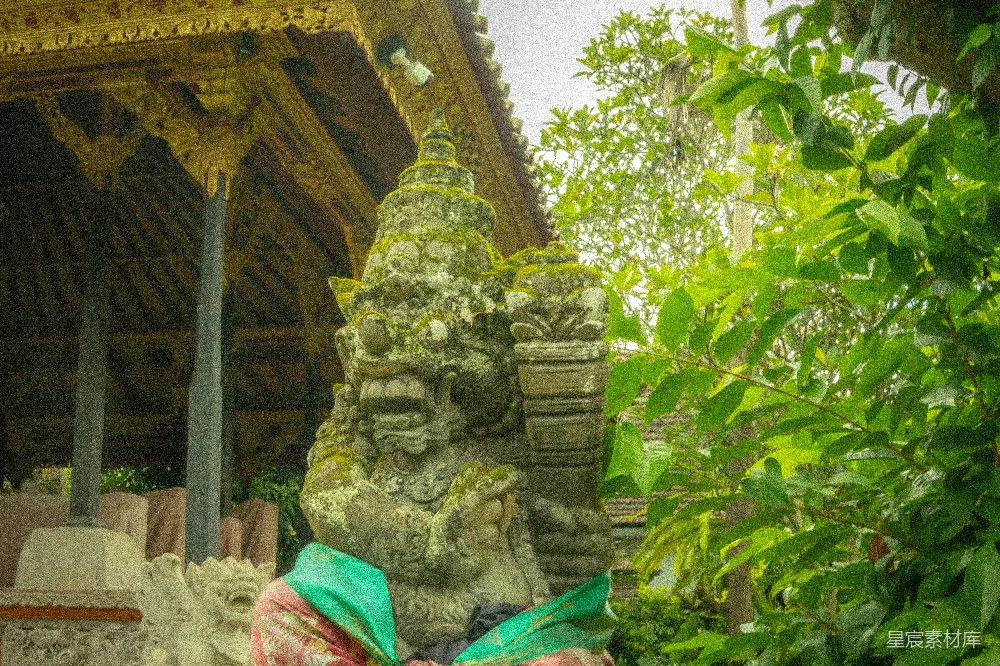高清摄影  青苔覆盖的石雕矗立在郁郁葱葱的绿叶和传统寺庙之间。