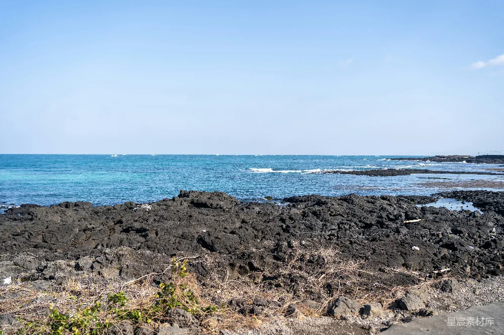 高清摄影  岩石海滩，背景中有一片水域。