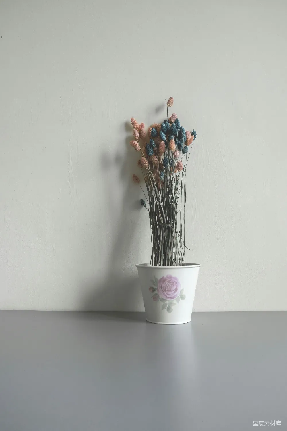 高清摄影  在墙边有几盆白色花盆中插着粉色和蓝色的人造花。