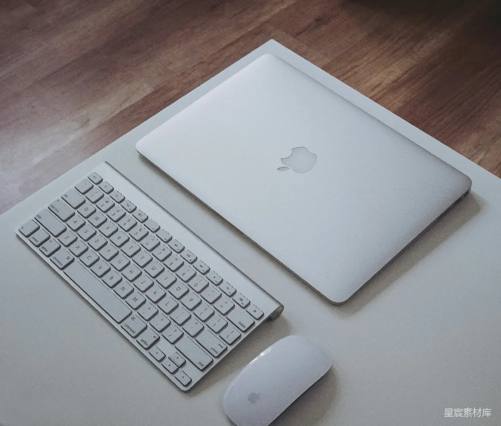 高清摄影  银色的MacBook靠近Apple Magic Keyboard和Apple Magic Mouse，放在白色表面上。