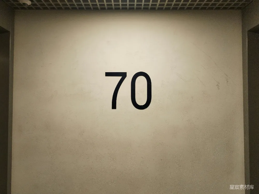 高清摄影  一面白墙上有黑色的数字“70”。