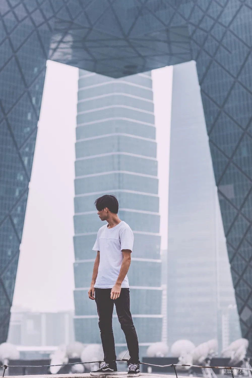 高清摄影  一个穿着白色圆领T恤的男人站在建筑物附近。