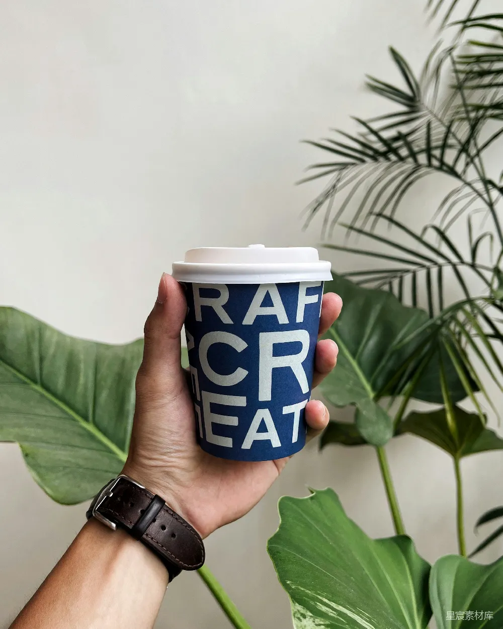 高清摄影  一只手拿着一个咖啡杯，咖啡杯上写着“Rah Creat”。