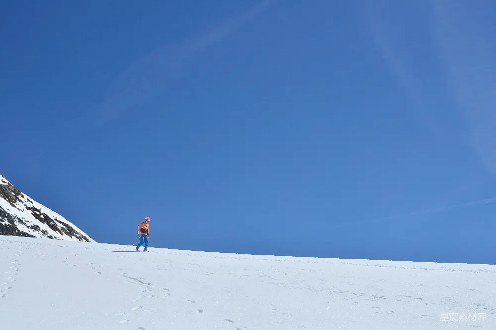 高清摄影  在晴朗的蓝天底下，一个人在雪地里行走。