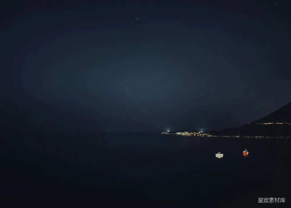 高清摄影  夜晚，远处的灯光在黑暗的海洋上闪烁。