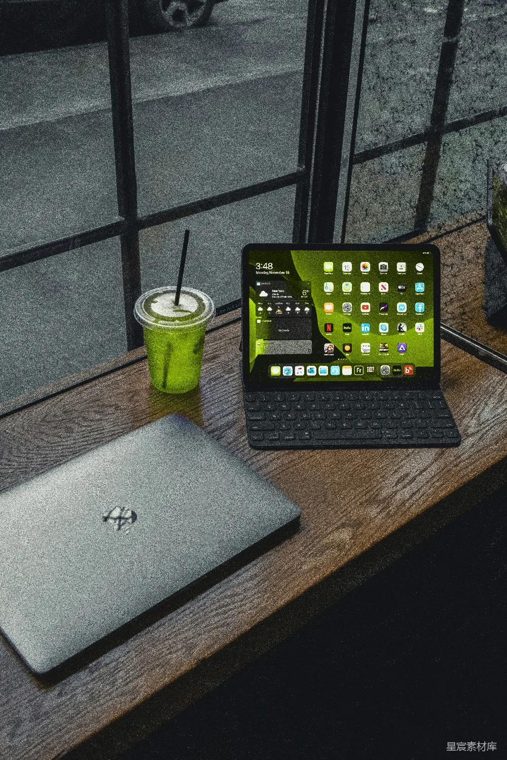 高清摄影  MacBook Pro 放在棕色木桌旁的绿色塑料杯旁边