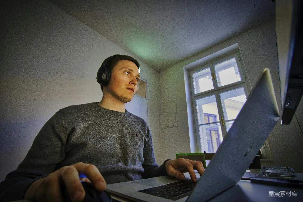 高清摄影  男人使用MacBook和无线耳机