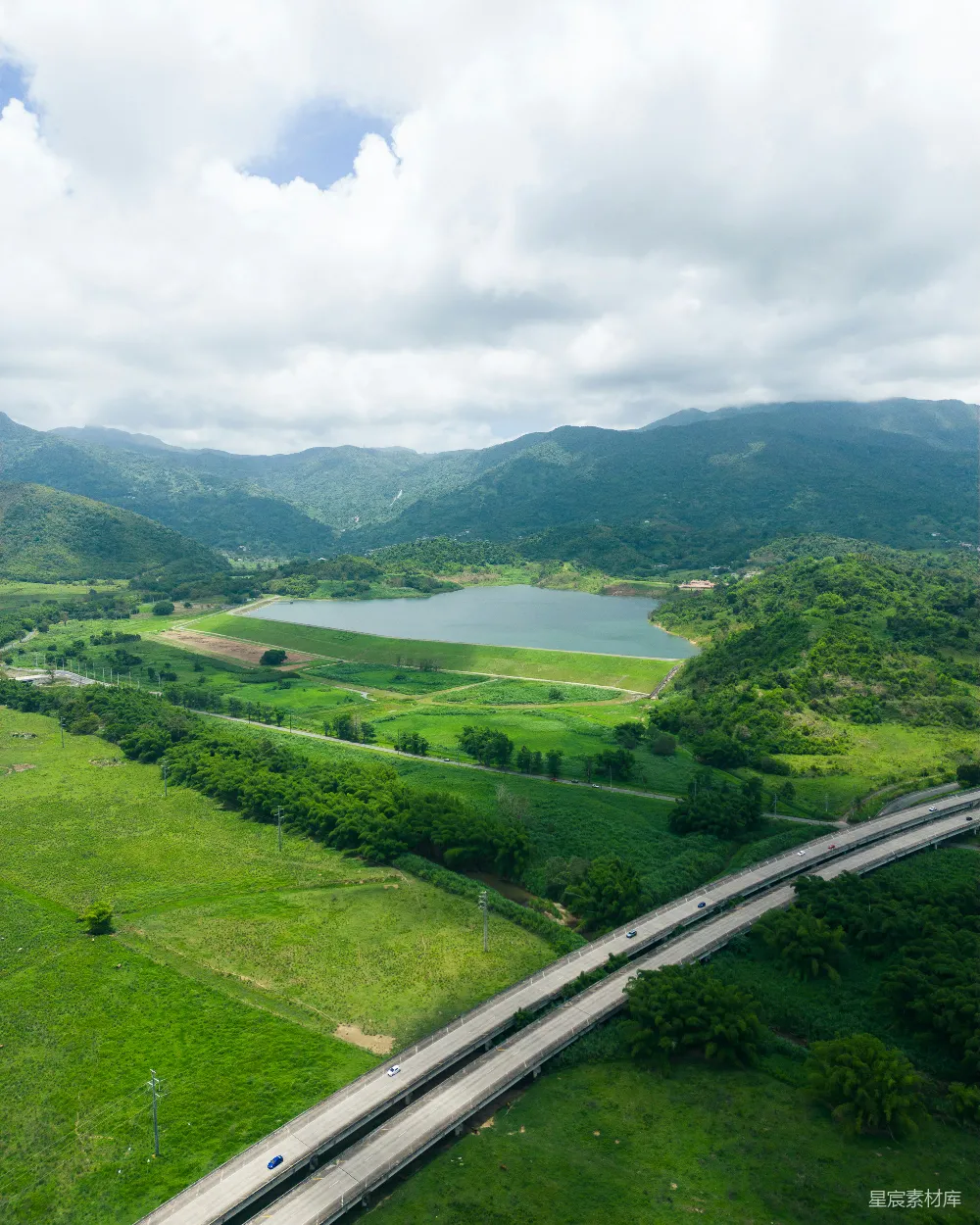 高清摄影 自然景观 航拍视角 绿色生态 公路交通 宁静乡村 山间湖泊与高速公路的和谐景象
