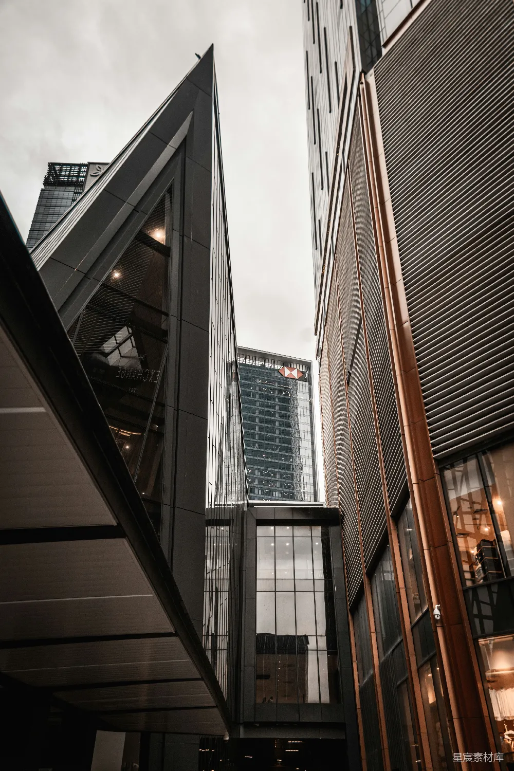 这张图片展示了现代化城市的建筑景观，高楼大厦错落有致，玻璃幕墙反射出天空的光影，给人一种繁华都市的感觉。视角从低角度仰视，强调了建筑物的高耸与现代感。适合用于城市规划、建筑设计或商务活动的背景图片。