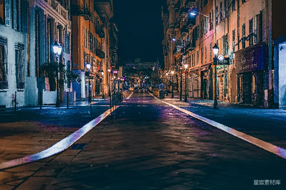 这张图片展示了夜晚宁静的街道景象。两侧是高大的建筑，灯光柔和，街道上没有行人和车辆，营造出一种静谧而神秘的氛围。街道两旁的路灯和建筑物的灯光交织在一起，形成了美丽的光影效果，给人一种宁静而祥和的感觉。这幅图适用于表现城市夜景、建筑美学或夜间