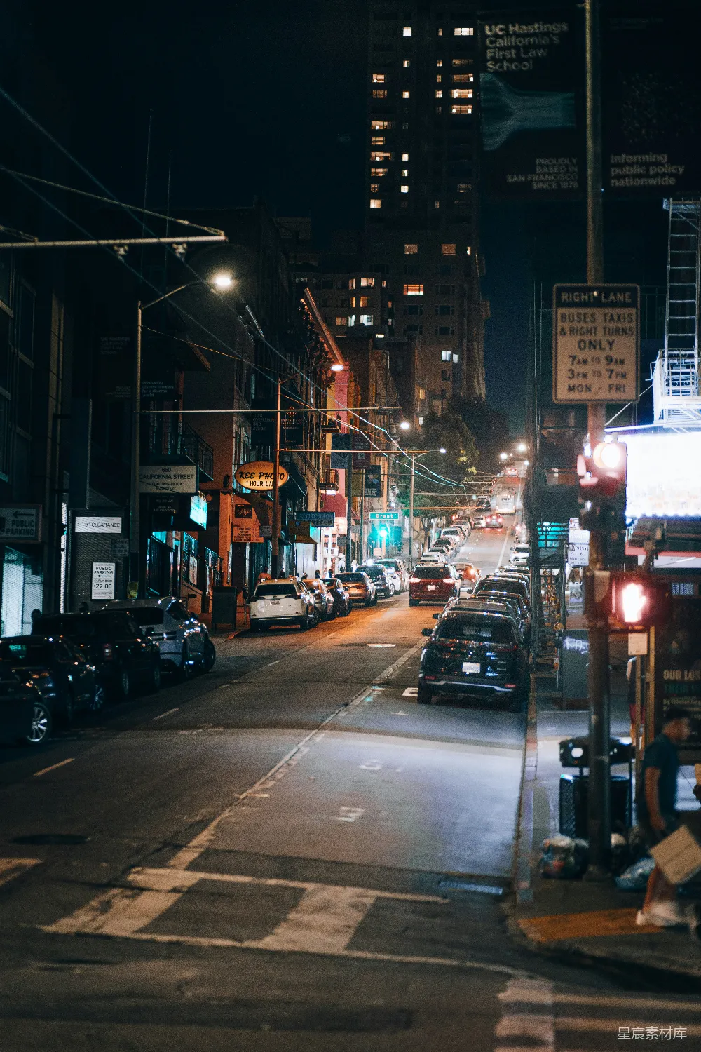 这张照片展示了一个城市的夜晚街道，两旁的建筑物灯火通明，街道上停满了车辆，街道上的灯光和建筑物的灯光交相辉映，营造出一种宁静而充满活力的氛围。适合用于城市生活、夜晚场景或都市夜景的视觉元素。