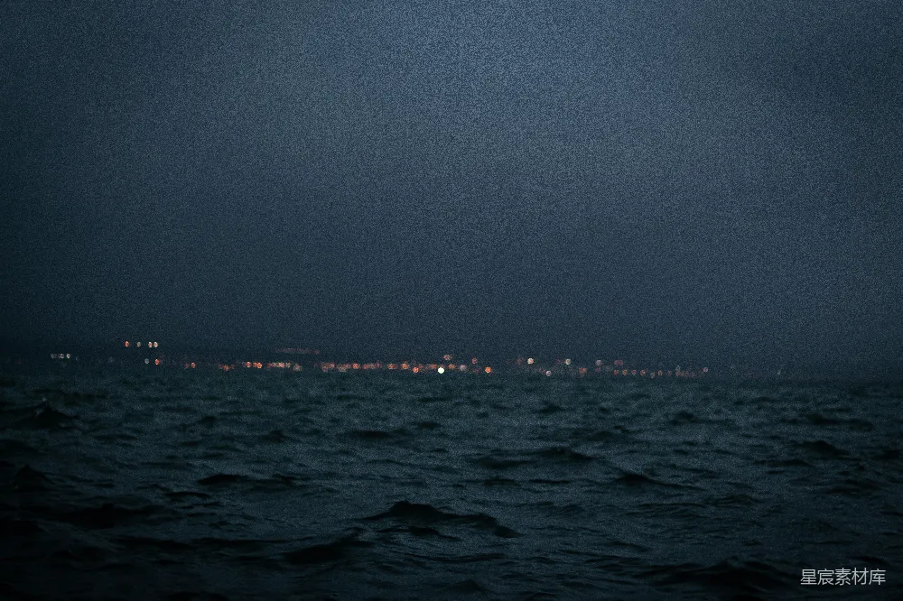 图片展示了一个夜晚的海景，海面波光粼粼，远处的城市灯光在夜空中闪烁，营造出一种宁静而神秘的氛围。适合用作夜晚旅行或城市与自然交融主题的背景图片。