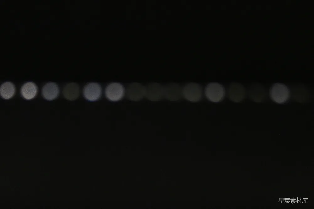 这张图片展示了夜晚的光点效果，背景是深邃的黑色，前景中是一排模糊的光点，形成了一个宁静而抽象的夜景画面。这种效果常用于艺术摄影和电影中，营造出一种神秘和梦幻的氛围。