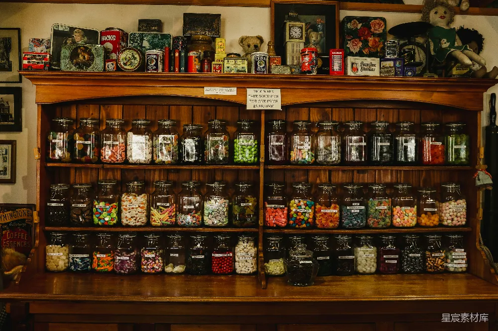 这张图片展示了一间复古风格的糖果店，木质的展示柜上摆满了各种形状和颜色的糖果，每个玻璃罐子上都贴有标签。墙上还挂有一些老式的装饰品和玩具，营造出一种怀旧的氛围。适合用于展示复古风格的店铺或家庭装饰。