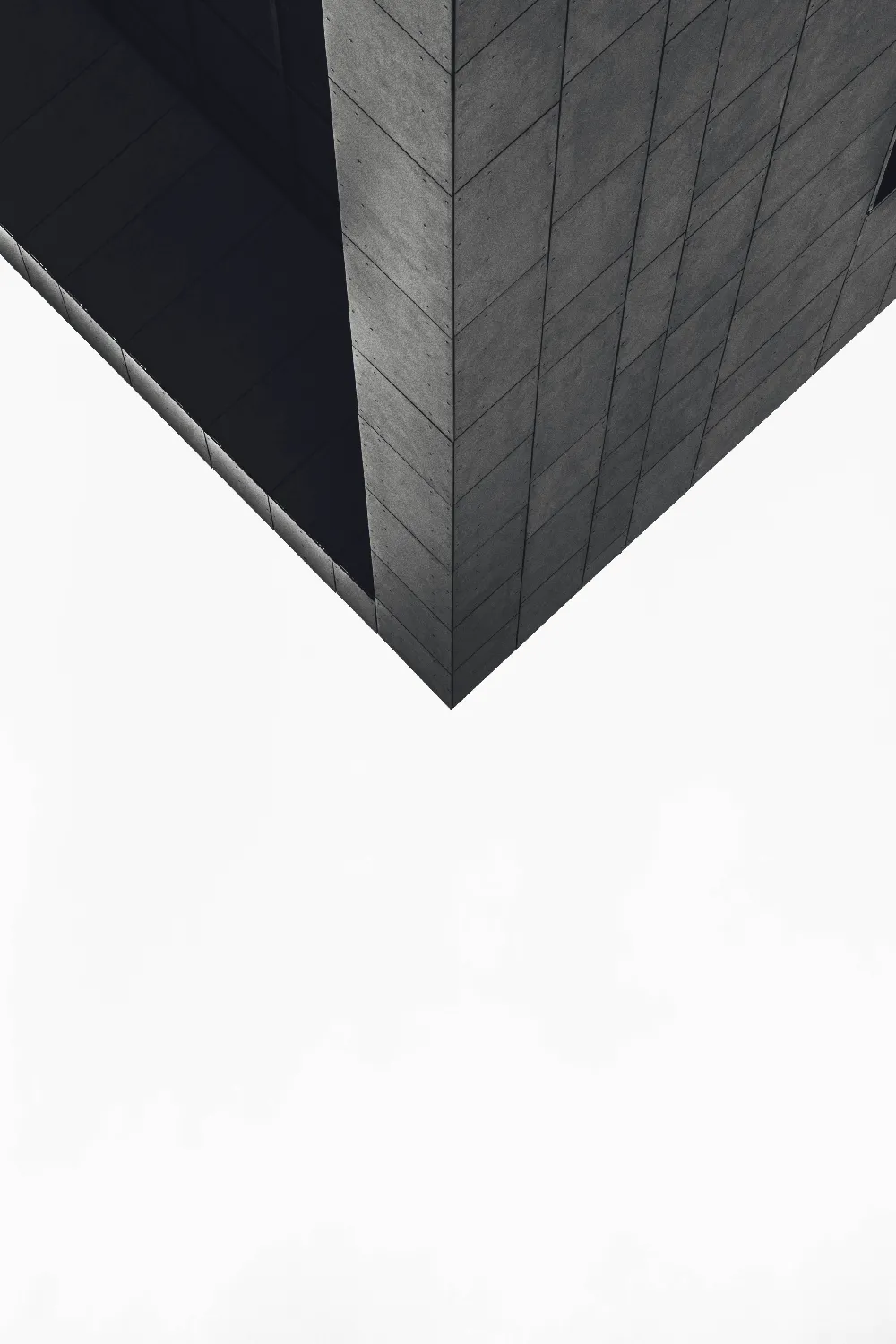 这张图片展示了建筑的一个几何角落，以简洁的灰色调和几何线条为特点，营造出一种现代和简约的视觉效果。适合用于建筑、设计或城市风格相关的素材展示。