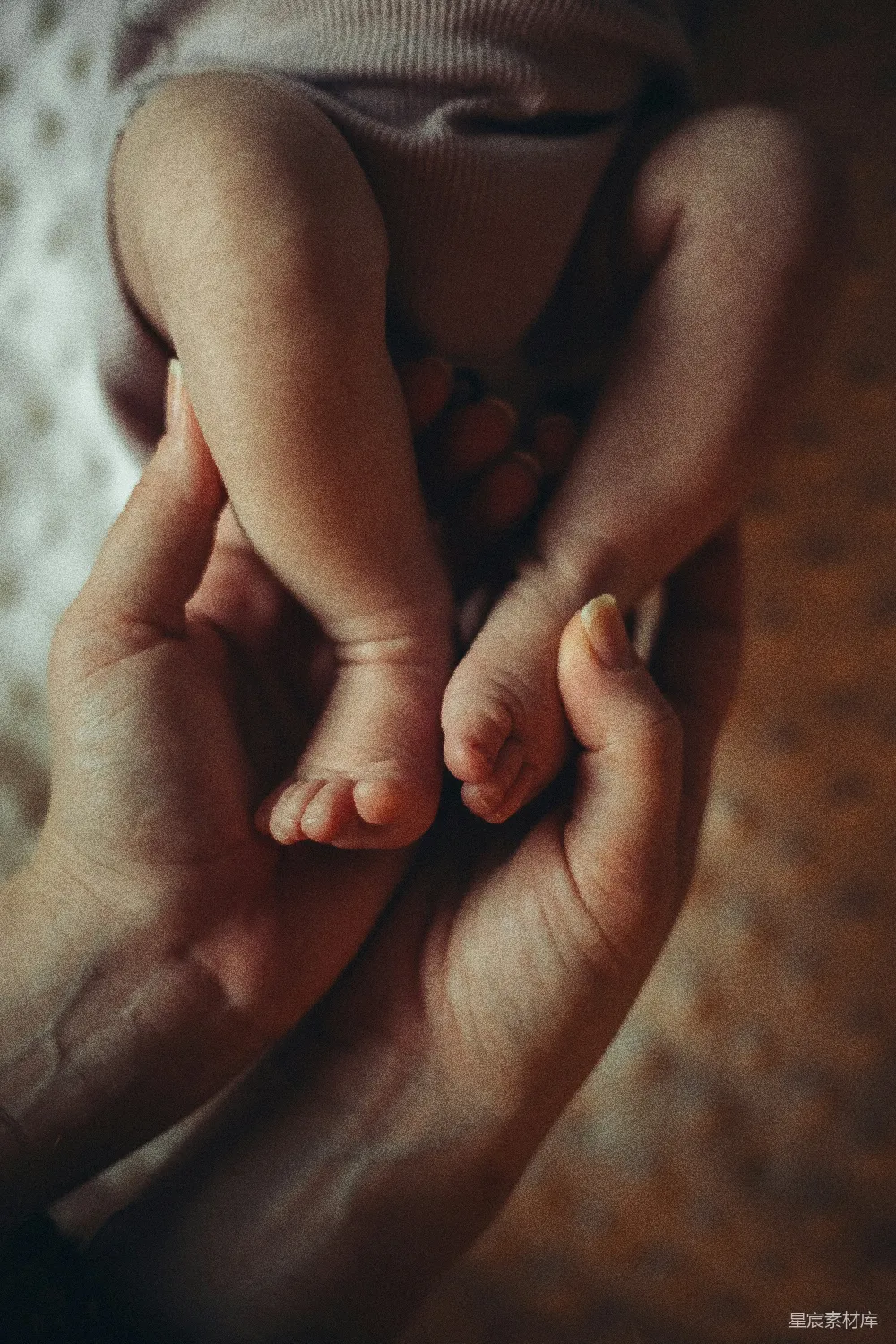 这张图片捕捉到了一个温馨的瞬间：一只成人的手温柔地托着一个婴儿的小脚。柔和的光线和温暖的色调营造出一种宁静而充满爱意的氛围，体现了亲情的温暖和生活的美好。这幅画面非常适合用作家庭相册、婴儿纪念册或是表达爱意的背景图。