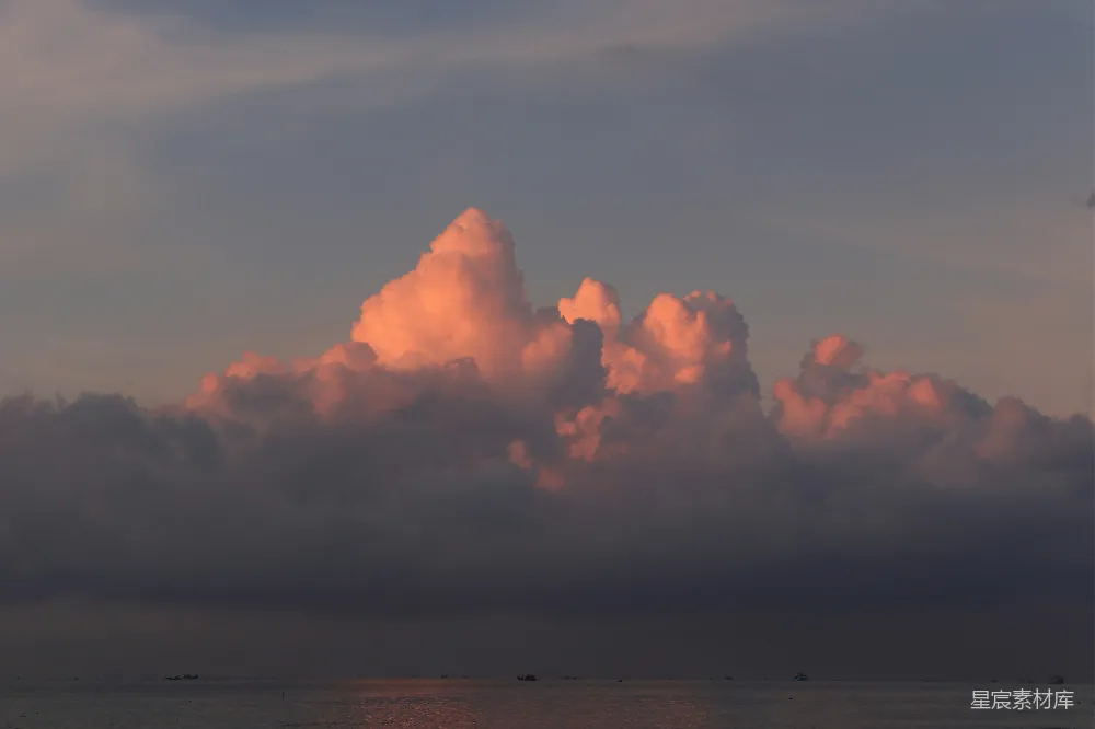 图片展示了一个日落时分的云海景象，天空中大片的云层被夕阳染成了橙红色，与远处平静的海面形成鲜明对比。这种景象通常出现在黄昏时分，给人一种宁静而美丽的视觉享受。