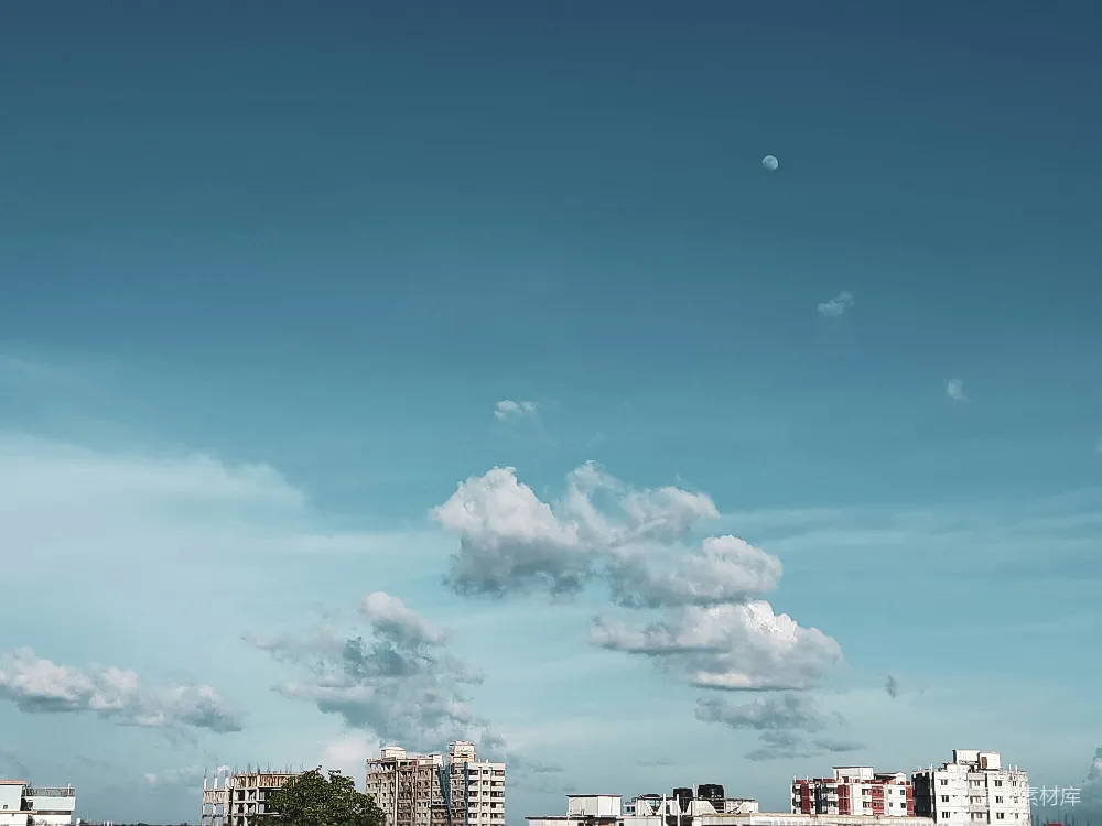 这张图片展示了城市上空的宁静景象，天空中漂浮着几朵白云，一轮明月高挂，增添了画面的宁静与诗意。下方是现代化的建筑群，与天空的宁静形成了鲜明对比。适合用作城市生活与自然和谐的背景素材。