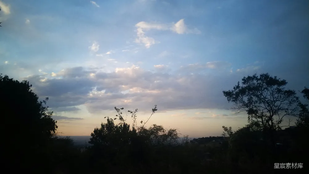 这张图片展示了夕阳下的云海景象。天空中云彩厚重，夕阳的余晖洒在云层上，形成了美丽的金色光影。地平线处树木的剪影与天空形成鲜明对比，给人一种宁静而祥和的感觉。适合用作自然风光的背景图片，或用于表达宁静、放松的主题。