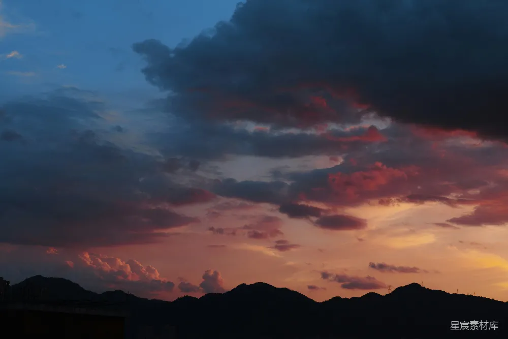 这张图片展示了傍晚时分，夕阳的余晖洒在山峦之上，天空被染成了绚烂的橙红色。云层在夕阳的映照下呈现出丰富的层次感，山的剪影与天空形成了鲜明的对比。适合用作自然风光的背景图片，展现宁静与和谐的自然之美。
