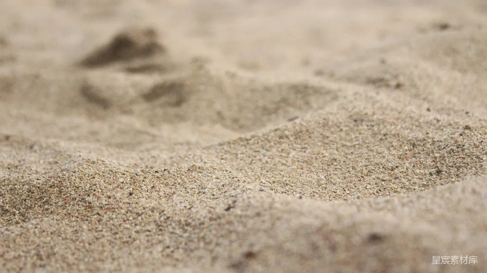 这张图片展示了沙滩上的细腻沙粒，沙粒颗粒均匀，颜色为浅褐色，背景虚化，突出了沙粒的质感和自然之美。适合用于自然风光、旅游宣传或与沙滩相关的主题背景。