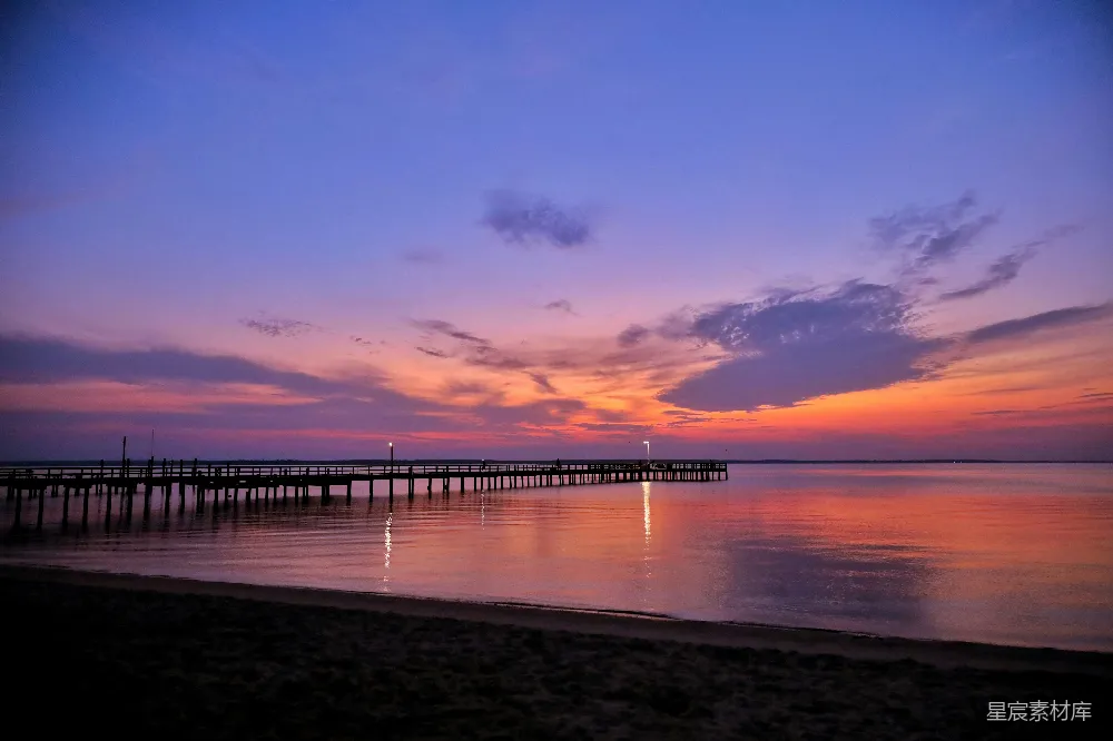 高清摄影  ```json {   title: 黄昏时分的码头与宁静的海滩,   keys: [夕阳, 海滩, 码头, 宁静, 自然美景],   descs: 这张图片展示了黄昏时分的海滩景色。天空被夕阳染成了