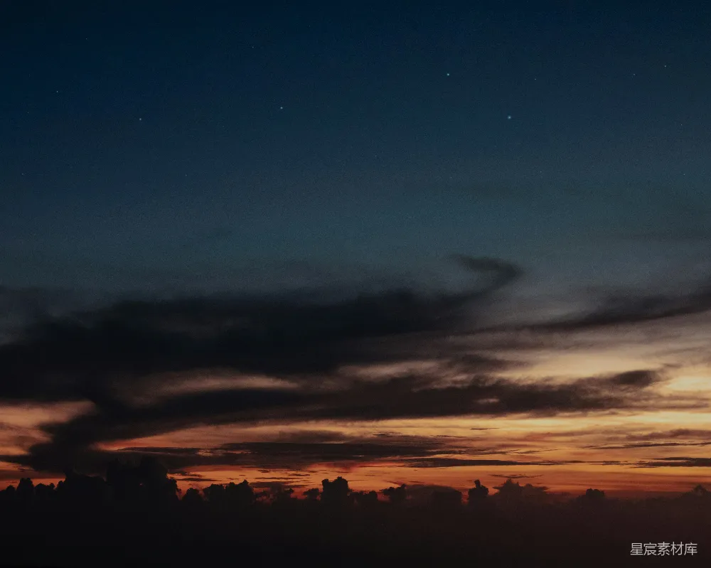 这张图片展示了一个宁静的夜空，其中点缀着点点星光和美丽的晚霞。天空从深蓝色渐变到橙黄色，形成了一个梦幻般的场景。云层在地平线上方形成柔和的轮廓，为整个画面增添了一种静谧和神秘的氛围。这张图片非常适合用作自然风光的背景，或者在社交媒体上分享，