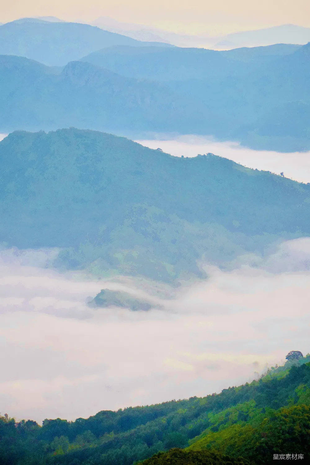 图片展示了一片宁静的自然风光，山峦连绵起伏，山顶被薄雾笼罩，远处的山脉若隐若现，给人一种宁静而神秘的感觉。清晨的光线柔和，为整个画面增添了一层梦幻的色彩。适合用于自然风光、旅行、摄影等场景。